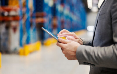 Close up of a businessman's hand scrolling on tablet in warehous